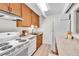 A well-lit kitchen with white appliances, wood cabinets, and neutral countertops and light wood floors at 8060 E Girard Ave # 311, Denver, CO 80231
