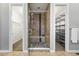Spacious bathroom with glass shower, neutral tile, and shelving for ample storage between closets at 15377 W Iliff Dr, Denver, CO 80228
