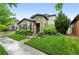 Beautiful stone house with well-maintained lawn, lush landscaping, and inviting curb appeal at 15377 W Iliff Dr, Denver, CO 80228