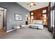 Modern main bedroom with wood accent wall, a ceiling fan, and plenty of natural light from the windows at 15377 W Iliff Dr, Denver, CO 80228