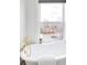 Bright bathroom featuring a modern white tub, decorative gold fixtures and a large window with a neighborhood view at 3249 W Fairview Pl # 207, Denver, CO 80211