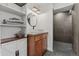 Bathroom featuring wooden cabinets, modern sink, a round mirror, and shower with large tiles at 19792 E Bates Dr, Aurora, CO 80013