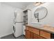 Bathroom featuring stacked washer and dryer, wooden cabinets, and round mirror at 19792 E Bates Dr, Aurora, CO 80013
