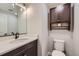 Modern bathroom features sleek vanity with an eye-catching mirror and a comfort-height toilet and overhead cabinet at 668 Sage Forest Ln, Monument, CO 80132