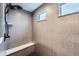 Modern bathroom with a sleek shower system, built-in bench, and tiled walls at 668 Sage Forest Ln, Monument, CO 80132