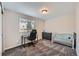 Comfortable carpeted bedroom with a desk, crib, and window overlooking the neighborhood at 668 Sage Forest Ln, Monument, CO 80132