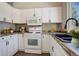 Functional kitchen with white cabinets, matching appliances, a tile backsplash, and dark countertops at 4723 S Pagosa Way, Aurora, CO 80015