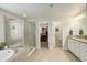 Bathroom featuring a glass-enclosed shower, soaking tub, and a double sink vanity with granite countertop at 6630 S Coolidge Ct, Aurora, CO 80016