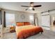 Main bedroom featuring a ceiling fan, bedside tables, and a sliding barn door at 6630 S Coolidge Ct, Aurora, CO 80016