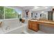 Bright bathroom with tub, wooden cabinets, and lots of natural light from the large window at 7027 Chestnut Hill St, Highlands Ranch, CO 80130