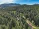 Scenic aerial perspective showcases a residence embraced by verdant forest and distant mountain views at 28251 Shadow Mountain Dr, Conifer, CO 80433