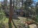Backyard with a patio, stone path, swing set, and mature trees at 28251 Shadow Mountain Dr, Conifer, CO 80433