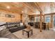 Comfortable living room with a sectional sofa, wood walls and a table with chairs in background at 28251 Shadow Mountain Dr, Conifer, CO 80433