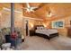 Bedroom with a fireplace, wood paneling, ceiling fans, and large windows at 28251 Shadow Mountain Dr, Conifer, CO 80433