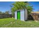 Backyard shed with a contrasting bright green door adding a pop of color to the landscape at 9411 Rose Ct, Thornton, CO 80229