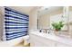 Bathroom features a sink, shower with blue striped curtain, and white cabinets at 9353 E 146Th Ave, Brighton, CO 80602