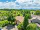 An aerial view of a house with a green area, a creek, many trees, and mountains in the background on a sunny day at 10478 W 82Nd Ave, Arvada, CO 80005