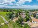 Aerial shot of neighborhood featuring mature trees, a creek, walking bridge, and a scenic lake backdrop on a sunny day at 10478 W 82Nd Ave, Arvada, CO 80005