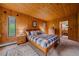 Cozy bedroom with knotty pine walls and ceiling plus a plaid bedspread at 26085 Amy Cir, Conifer, CO 80433