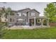 Spacious backyard featuring a covered patio, seating area, lush green grass, and mature trees at 10230 Lauren Ct, Highlands Ranch, CO 80130