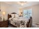 Cozy bedroom with a wooden bed frame, decorative quilt, bedside table with a lamp, and a window at 10230 Lauren Ct, Highlands Ranch, CO 80130