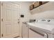 Bright laundry room with modern washer and dryer, overhead shelving, and a white door at 10230 Lauren Ct, Highlands Ranch, CO 80130
