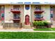 Charming condo building featuring balconies with red trim and well-maintained landscaping at 12132 Huron St # 203, Denver, CO 80234