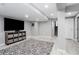 Finished basement with a mounted TV, stylish rug, and access to a staircase and a closet at 6386 S Pierson St, Littleton, CO 80127