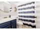 Modern bathroom with white fixtures, navy vanity, updated shower with striped curtain, and gold accents at 6386 S Pierson St, Littleton, CO 80127