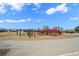 Scenic shot of a large playground with colorful equipment, under a bright blue sky with scattered clouds at 4887 Raven Run, Broomfield, CO 80023