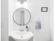 Small bathroom with round mirror and white vanity at 1503 S Buckley Way, Aurora, CO 80017