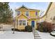 Beautiful two-story yellow house with a blue door and snowy front yard at 1503 S Buckley Way, Aurora, CO 80017