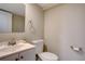 Cozy half-bathroom featuring a white vanity, mirror, and standard toilet at 7249 S Iris Ct, Littleton, CO 80128