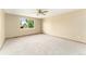 Bedroom with neutral carpet, ceiling fan, and a large window overlooking lush trees at 11335 W 54Th Ln, Arvada, CO 80002