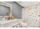 This bathroom offers a single sink with white cabinets, a gray wall and shower with patterned curtain at 16160 E 119Th Ave, Commerce City, CO 80022