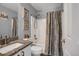 Well-lit bathroom featuring a granite vanity top, framed decor, and shower with patterned curtain at 2432 S Genoa Way, Aurora, CO 80013