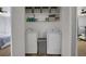 Laundry area showcasing a washer, dryer, shelves with storage, and access to a bedroom at 2432 S Genoa Way, Aurora, CO 80013