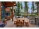 Spacious outdoor deck featuring wood furniture, a stone counter, and a wooded view, perfect for entertaining at 47 Forest Cir, Breckenridge, CO 80424