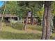 Exterior view of the home through a wooded area with tall trees and lush greenery at 11953 Us Highway 285, Conifer, CO 80433