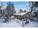 Backyard view of the home in winter surrounded by snow-covered trees at 11953 Us Highway 285, Conifer, CO 80433