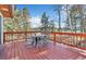 Wooden deck featuring outdoor dining furniture surrounded by tall trees and nature views at 11953 Us Highway 285, Conifer, CO 80433