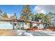 Exterior of a cozy home with an attached garage and a wooden deck surrounded by trees at 11953 Us Highway 285, Conifer, CO 80433