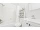 Bright white bathroom features a shower-tub combo, ladder shelving, and a modern vanity with sleek hardware at 677 Vrain St # 15, Denver, CO 80204