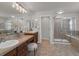 Bathroom featuring double sinks, wood cabinets, a glass shower, and decorative finishes at 10683 Amesbury Way, Highlands Ranch, CO 80126