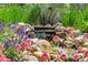 Close up of rock water feature with colorful surrounding flowers adding natural beauty and serene sound to the garden at 10683 Amesbury Way, Highlands Ranch, CO 80126