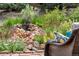 Picturesque water feature with a small waterfall surrounded by lush plantings and rocks, creating a tranquil garden retreat at 10683 Amesbury Way, Highlands Ranch, CO 80126