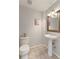 Cozy half-bathroom features a pedestal sink, decorative mirror, and neutral tile flooring at 7858 Oban Ct, Lone Tree, CO 80124