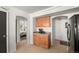 Kitchenette with tan cabinets, stainless fridge, and view into another room, adjacent to a bedroom at 4713 Perth St, Denver, CO 80249