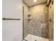Shower with glass door, tiled walls and showerhead, and floating shelves for extra storage at 7580 S Monaco Way, Centennial, CO 80112