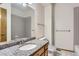 Bathroom featuring a granite countertop, wood cabinets, a large mirror, and neutral tile at 7580 S Monaco Way, Centennial, CO 80112